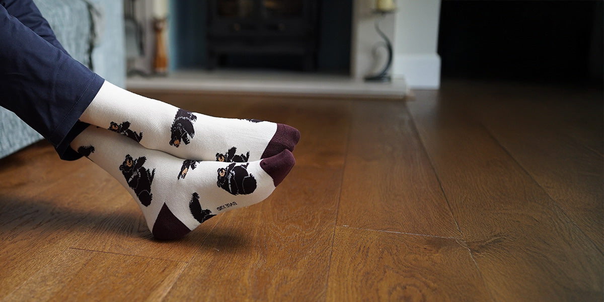 Person wearing white socks with black bear prints on a wooden floor.