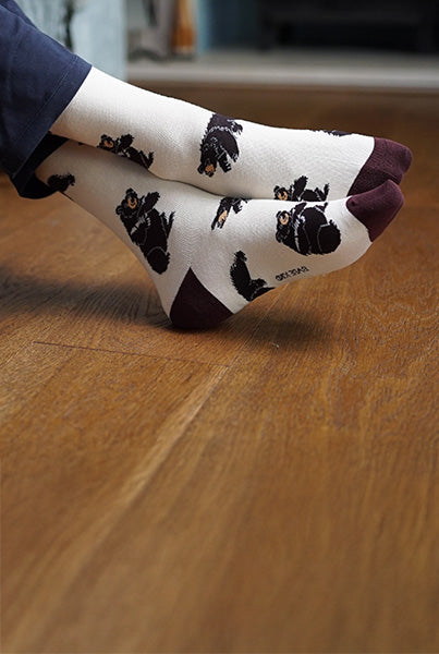 Person wearing white socks with black bear prints on a wooden floor.