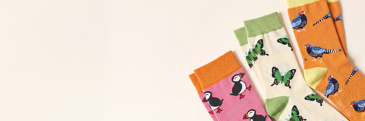 Three pairs of colorful socks with puffin and butterfly patterns on a light background