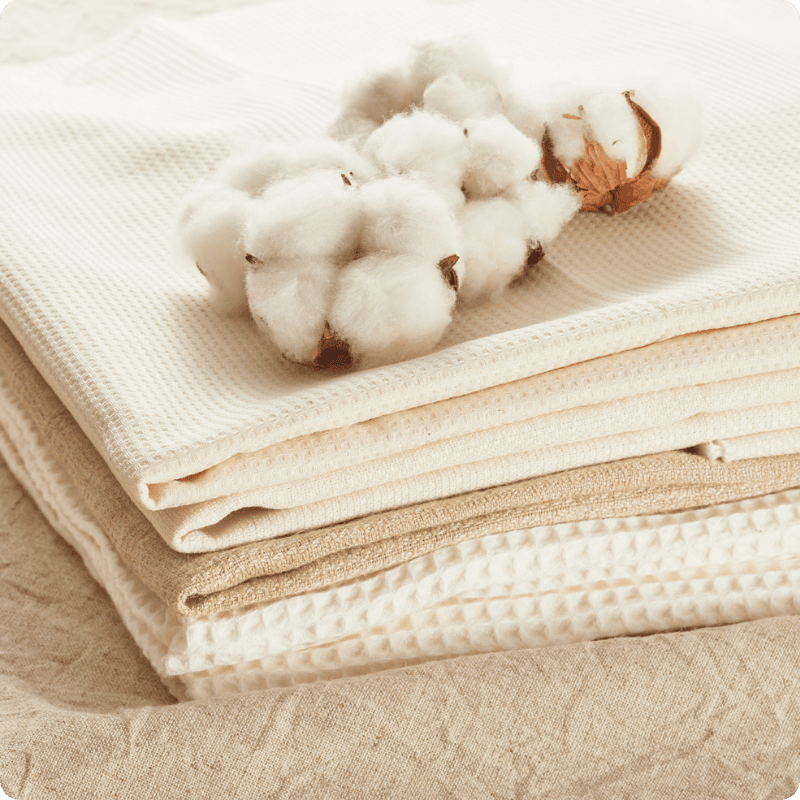 Stack of beige fabric with cotton bolls on top