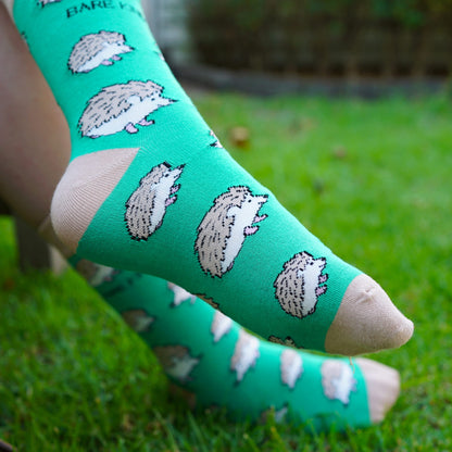 lifestyle image of model wearing green hedgehog bamboo socks outside on grass