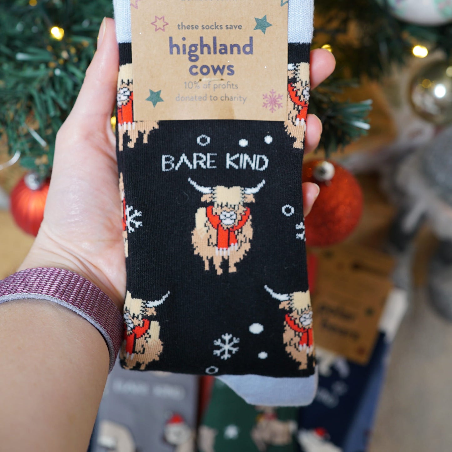 model holding the packaging of christmas highland cows bamboo socks in her hand