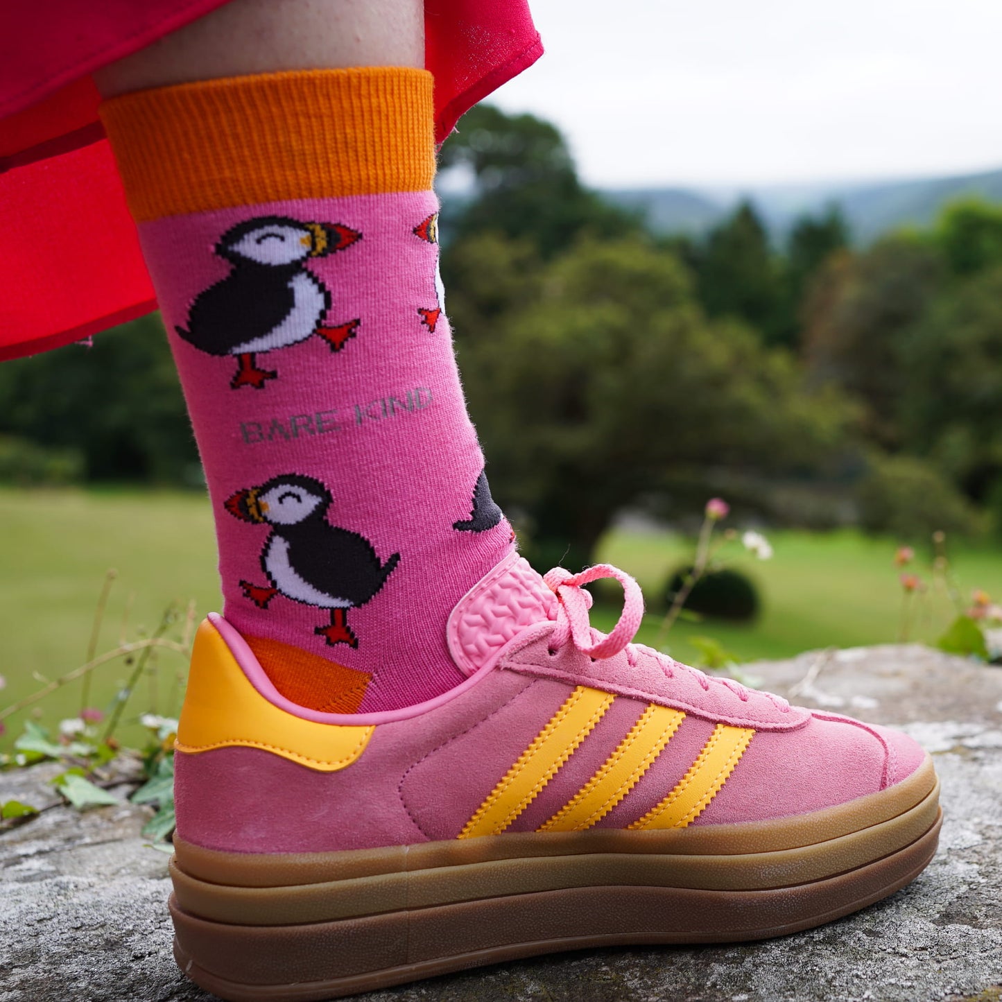 lifestyle image of model wearing pink puffin bamboo socks with pink and yellow trainers