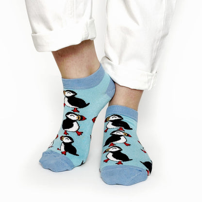 image of model wearing blue  puffin bamboo trainer socks with white trousers