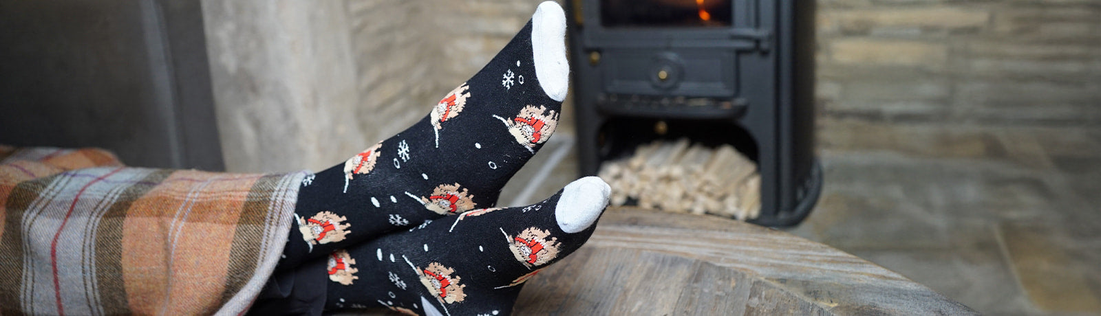 Person wearing socks with highland cows designs in front of a fireplace