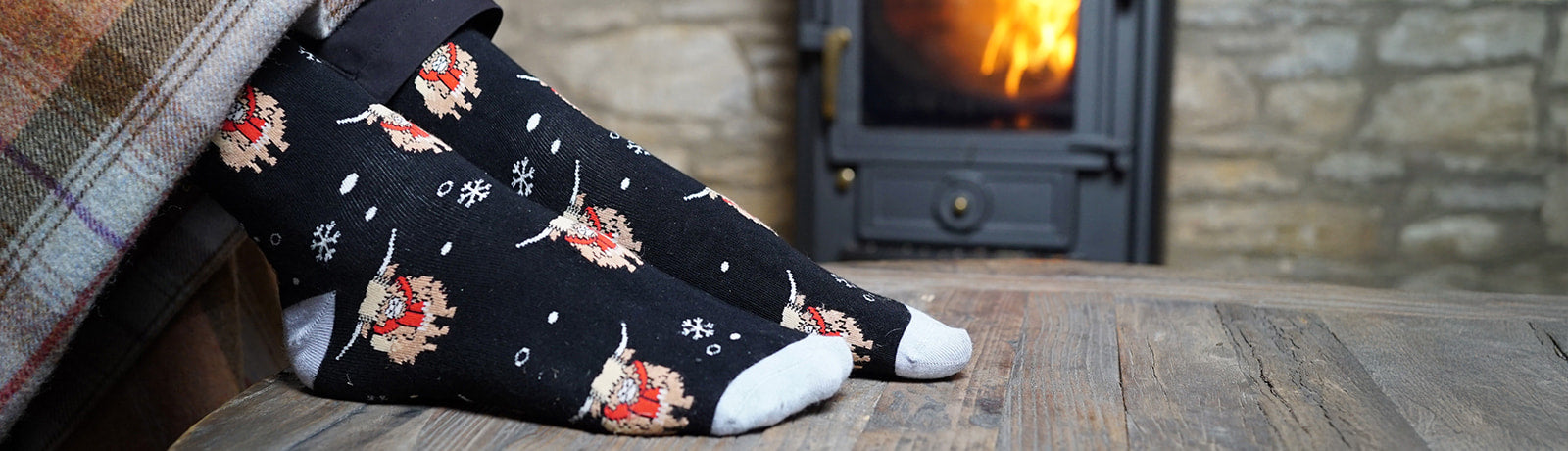 Person wearing socks with highland cows designs in front of a fireplace