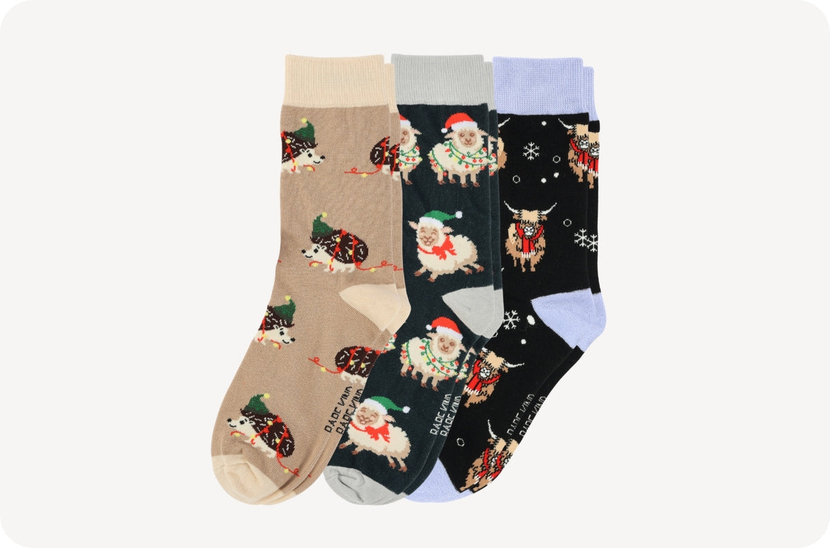 Three pairs of Christmas-themed crew socks displayed side-by-side on a light gray background. 