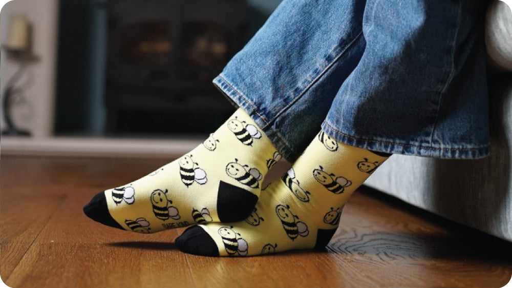 Person wearing yellow bee socks on a wooden floor.