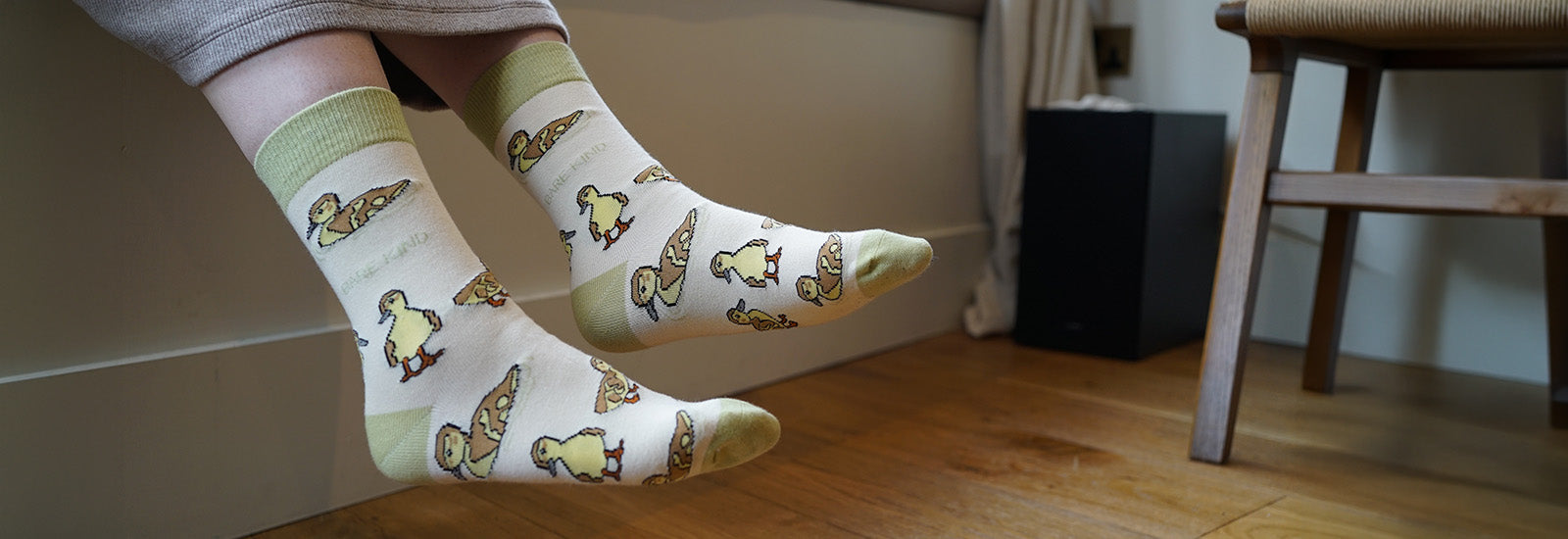 Person wearing socks with duck pattern on wooden floor