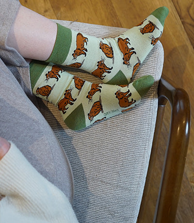 Person wearing green socks with capybara design.