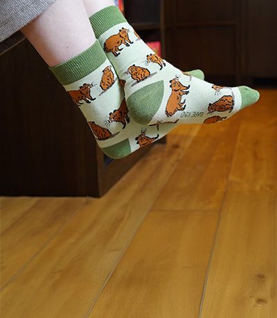 Person wearing green socks with capybara design.