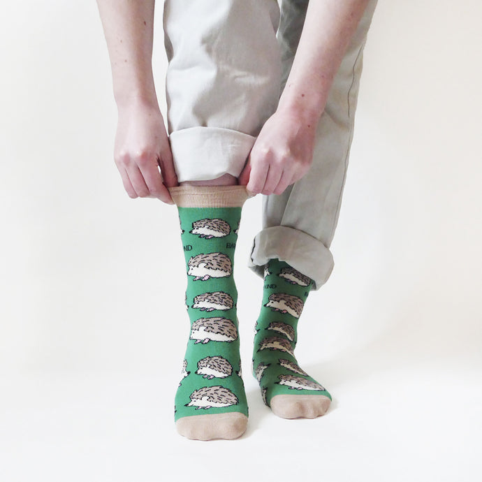 standing model pulling beige cuff of green hedgehog bamboo socks