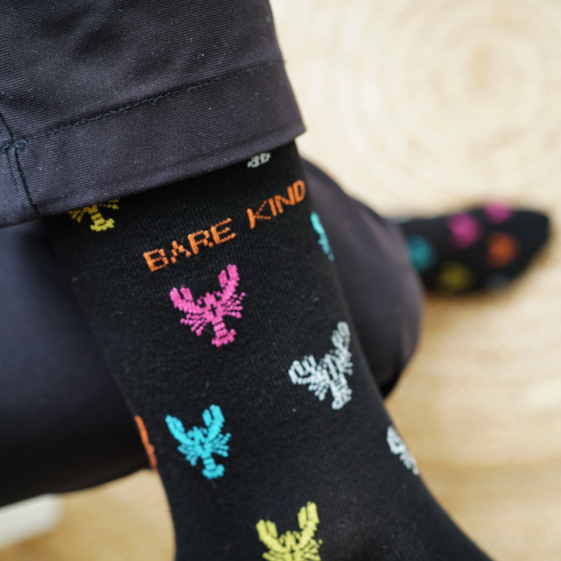 Model wearing Bare Kind bamboo socks, featuring small motifs of lobsters