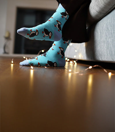 Blue puffin socks worn by a person on a wooden floor.