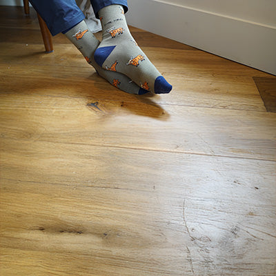 Green socks with blue toes and orange accents on a wooden floor.