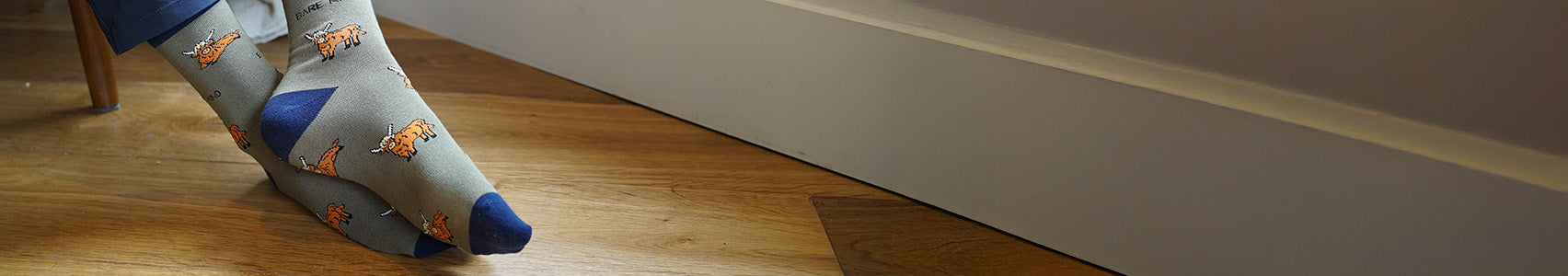 Green socks with blue toes and orange accents on a wooden floor.