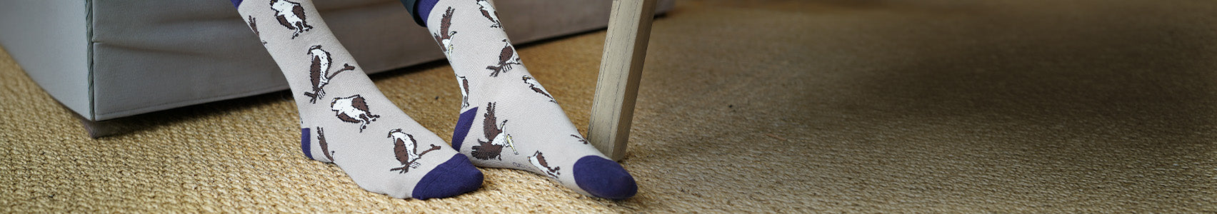 Person wearing socks with a pattern of feet and shoes on a carpeted floor.