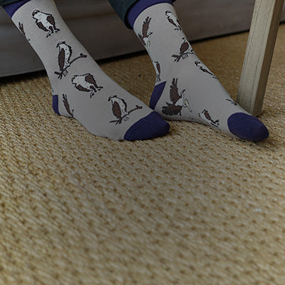 White socks with bird pattern worn by a person on a carpeted floor.