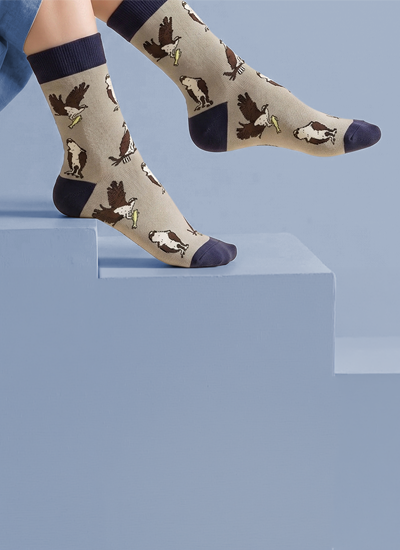 A pair of beige crew socks with a pattern of ospreys.