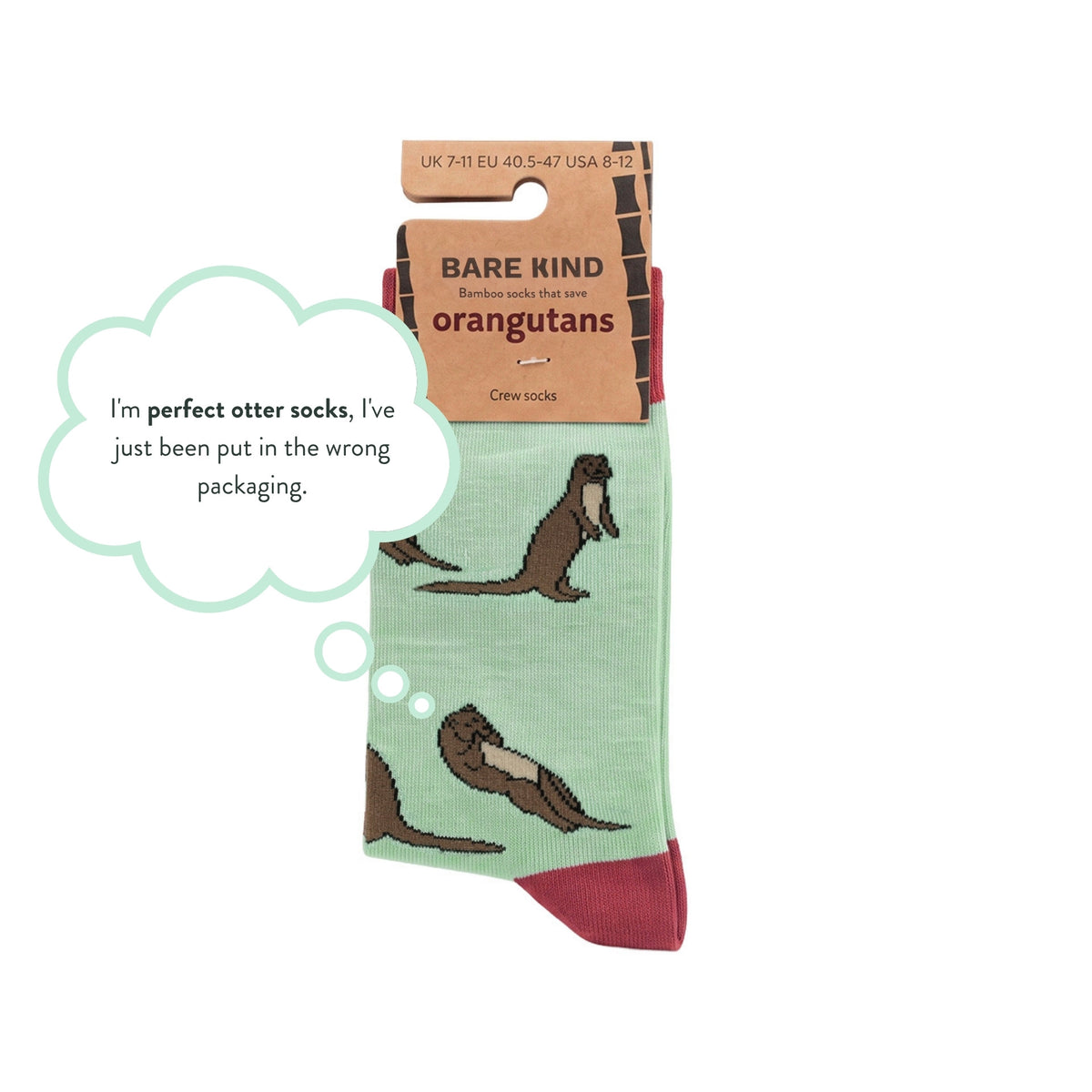 A pair of crew socks with a light green base and brown otter illustrations, attached to a cardboard hanger labeled 'BARE KIND'. A light blue speech bubble says, 'I'm perfect otter socks, I've just been put in the wrong packaging.