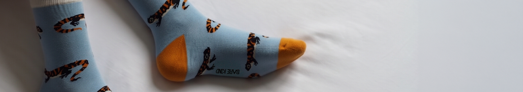 Light blue socks with orange toes and salamander pattern on a white surface