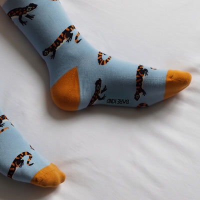 Light blue socks with orange toes and salamander pattern on a white surface