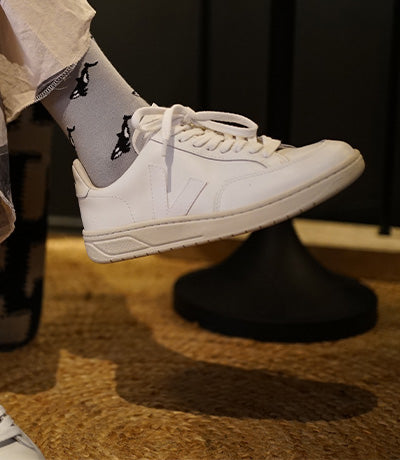 Person wearing white sneakers and small motif Orcas socks on a dark background