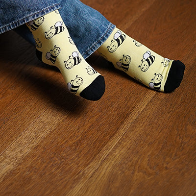 Person wearing bee socks on a wooden floor