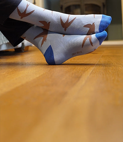 Blue socks with brown swift pattern on a wooden floor