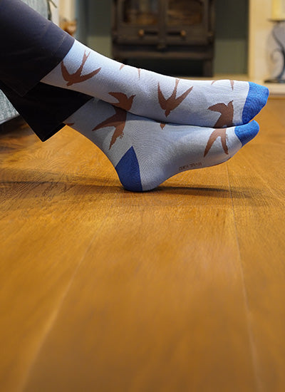 Person wearing socks with swift pattern on a wooden floor