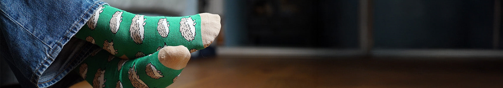 Green socks with hedgehog pattern worn on a wooden floor