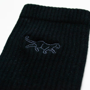 cuff closeup flat lay of ribbed black bamboo socks with panther embroidery on the cuff