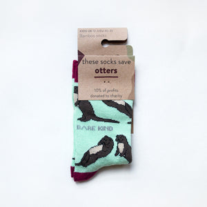 folded flat lay of pastel green otter socks for kids in 100% recyclable packaging