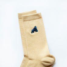 minimalist flat lay cuff closeup of pastel yellow ribbed bamboo socks with embroidered gorilla motif on the cuff