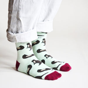 standing model wearing pastel green otter socks, side angle view