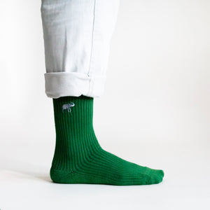 perfect side view of model wearing emerald green ribbed bamboo socks with embroidered elephant motif on the cuff