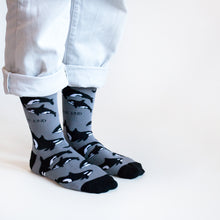standing model wearing black and grey orca bamboo socks, side angle view