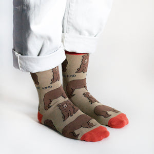 Model wears brown and red bamboo bear socks, side angle view, both feet on the floor as they stand