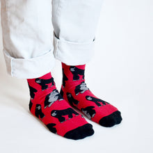 Standing model, side angle view, wearing red and black gorilla socks