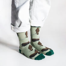 standing model wearing green eagle socks, side angle view 