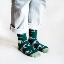 standing model wearing green snow leopard socks, side angle view
