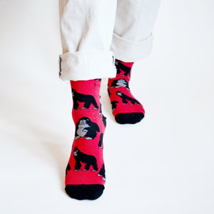 Standing model, front view, wearing red and black gorilla socks, right foot forward highlighting gorilla design
