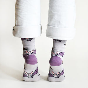 Back view of a model standing on their toes, wearing purple and grey bat bamboo socks
