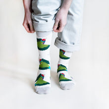 standing model wearing white gouldian finch bamboo socks, and pulling the right cuff up