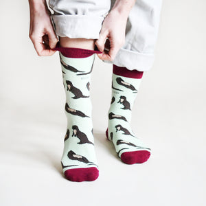 standing model pulling up pastel green otter socks from the cuff