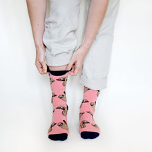 standing model wearing pink bamboo sloth socks, pulling on the navy cuff