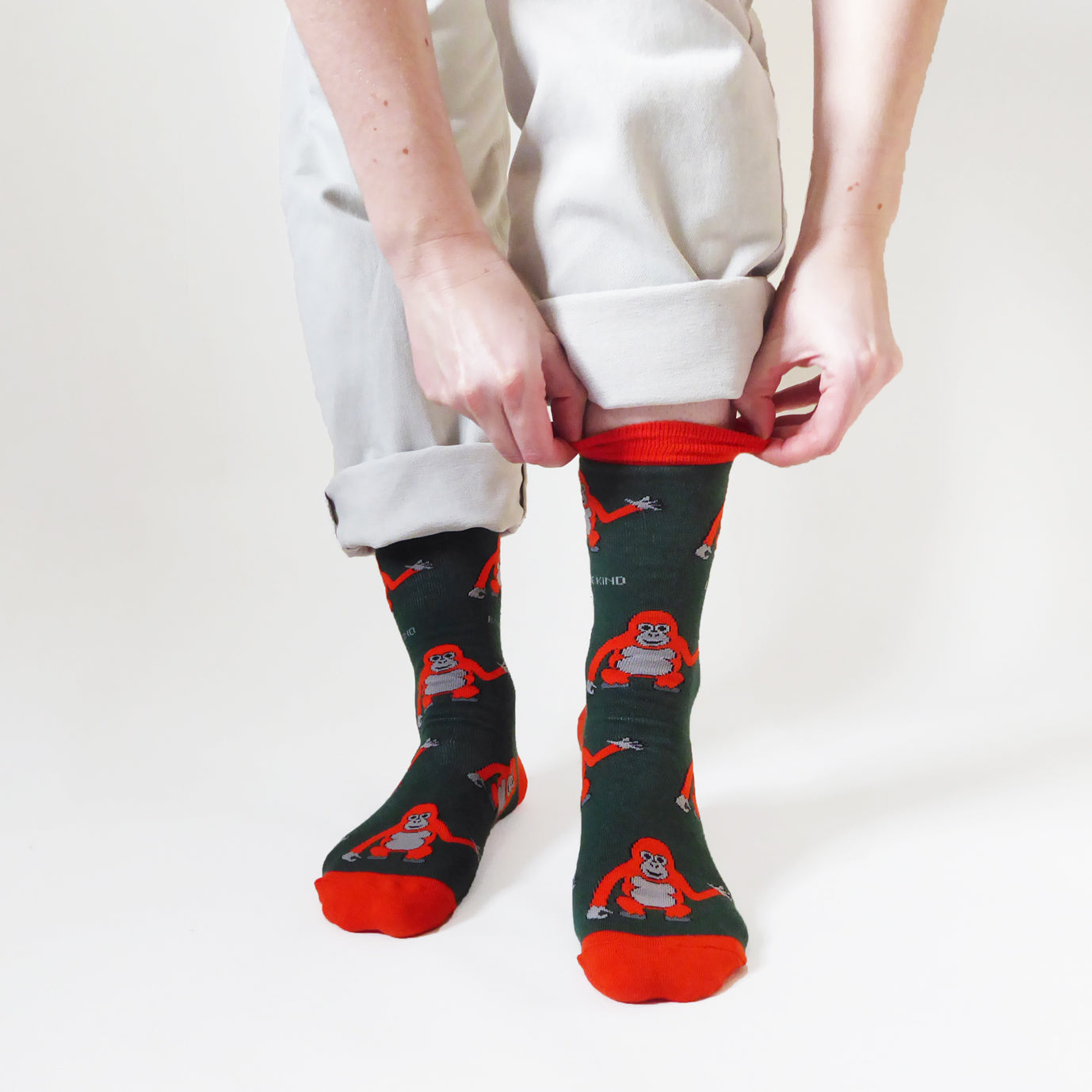 standing model pulling up dark green orangutuan bamboo socks from the cuff