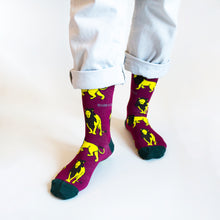 standing model wearing burgundy lion socks, front view, right foot forward and angled out 
