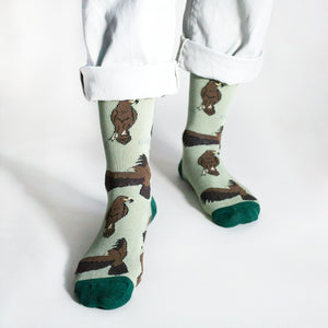 standing model wearing green eagle socks, front angle view with left foot forward