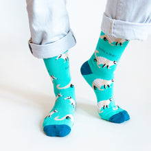 standing standing model wearing bright blue numbat socks, as the left heel is lifted, showcasing the side of the socks